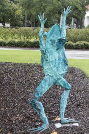 sculpture of a frog, about 5 feet tall, with its 'arms' upraised in joy looking skyward