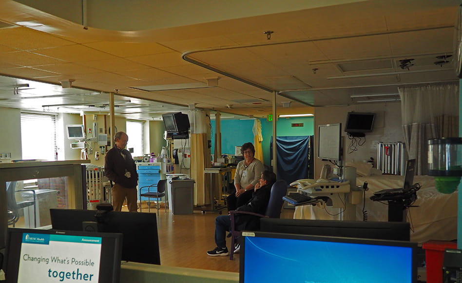 one doctor leans against a pole while two others sit in rolling chairs on a darkened and abandoned unit floor